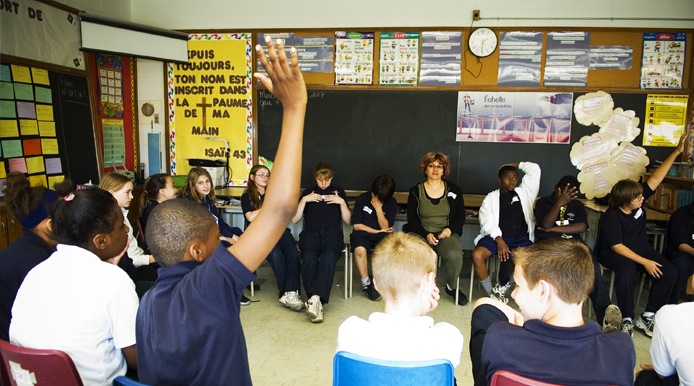 one kid in a class with his hand raised